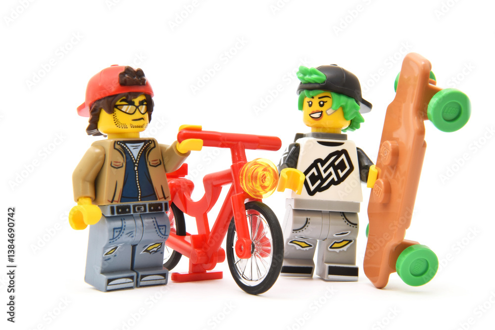 Obraz premium Lego minifigures of friends with bicycle and skateboard closed up isolated on white. Editorial illustrative image of popular plastic toy constructor for children.
