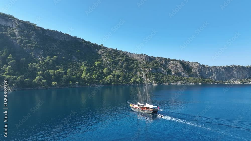 Aerial view of Gulet ship navigating the coastline under a blue sky Aerial view of Gulet ship navigating the coastline under a blue sky