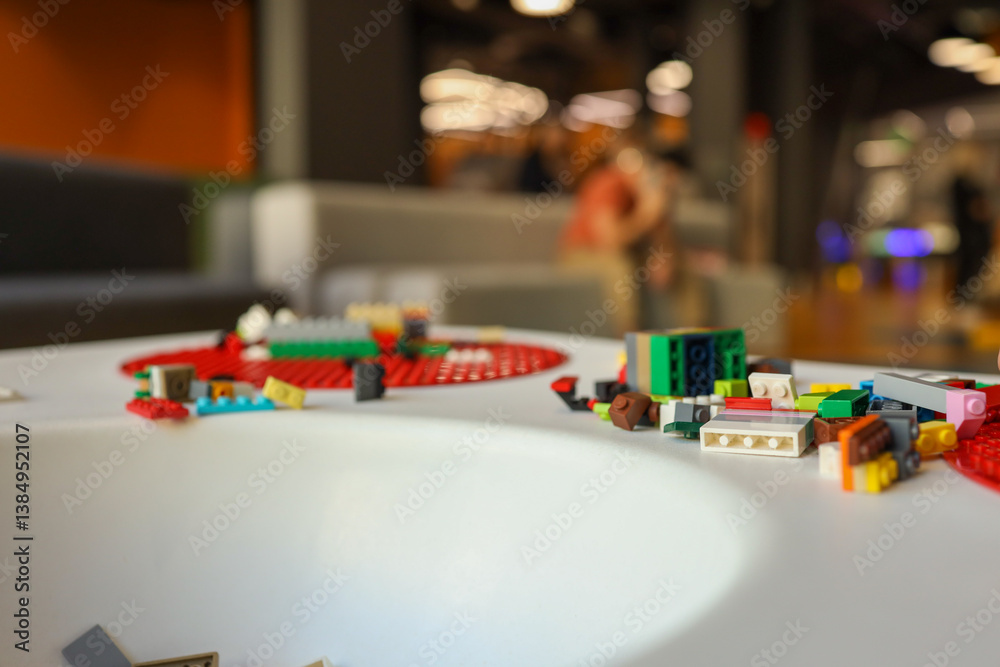 Modern playroom with a white children's table featuring red circular base plates, scattered building blocks, and bright yellow spherical stools Modern playroom with a white children's table featuring red circular base plates, scattered building blocks, and bright yellow spherical stools