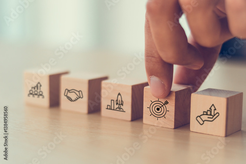 Business strategy concept. Wooden blocks with icons representing business strategy elements; teamwork, partnership, innovation and technology, target and growth. Business goal acheivement.