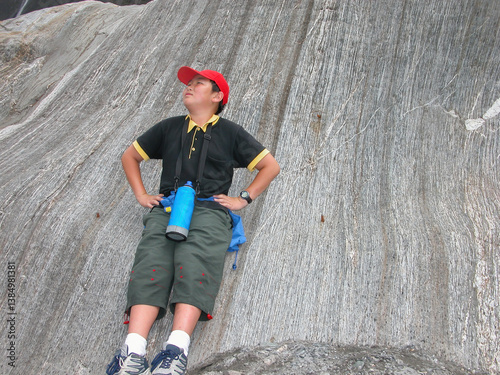 Obraz na płótnie Teenage boy leaning on glacier rock and posing for fun photos. Franz Josef Glacier. South Island. New Zealand. w salonie