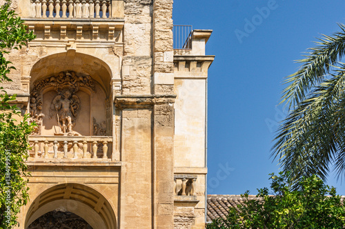 Ornate architectural detail of the palace of viana in cordoba, spain, featuring a statue of saint rafael and lush vegetation