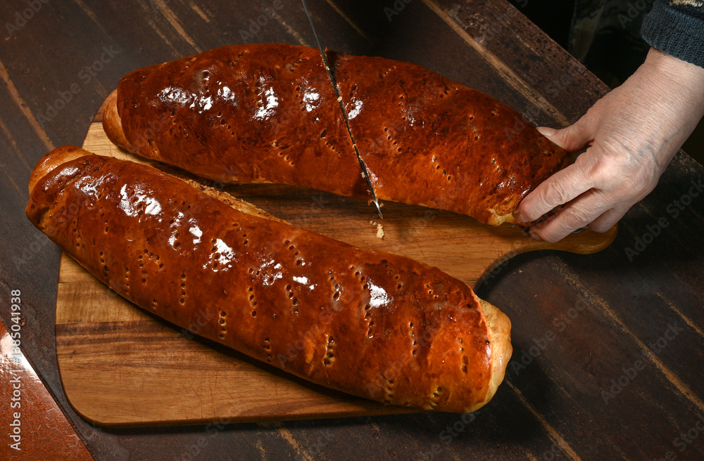 Freshly baked bread being sliced on a wooden board in a cozy kitchen setting during the afternoon