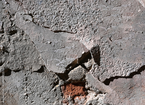 Obraz na płótnie Textured concrete wall featuring cracks and graffiti in urban setting during bright daylight w salonie