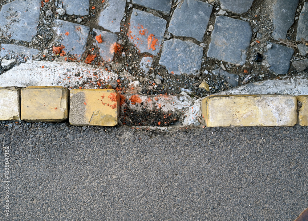 Uneven cobblestone path transitions into a smooth asphalt road