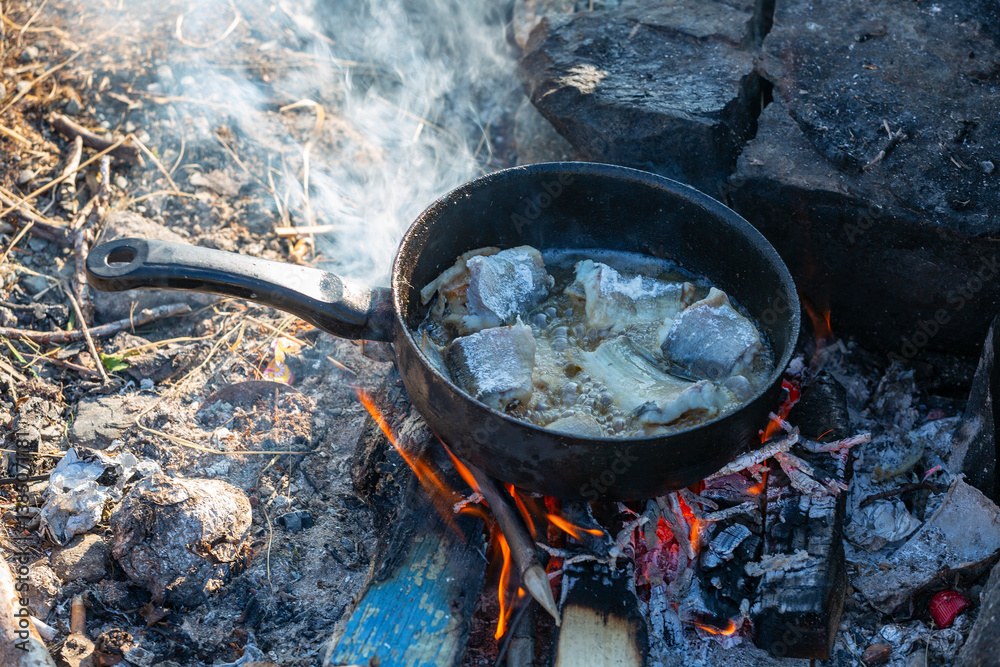 Fish is fried in a skillet on the fire