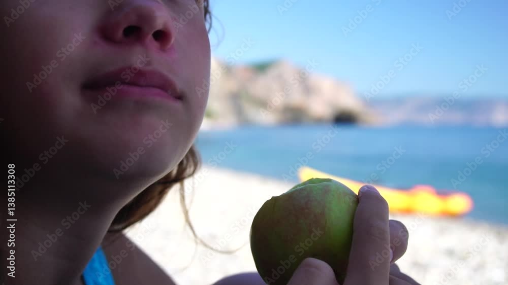 Close-Up of a Young Woman Eating an Apple on the Beach