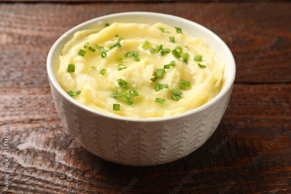 Tasty mashed potato with green onion in bowl on wooden table, closeup Tasty mashed potato with green onion in bowl on wooden table, closeup