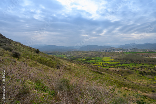 Exploring the serene hill landscapes with sprawling green fields and distant mountains under a cloudy sky