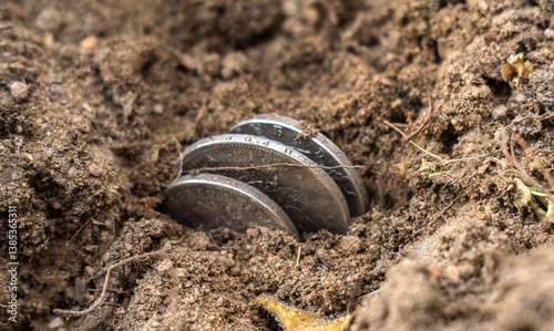 Fotografie A few coins partially buried in the ground