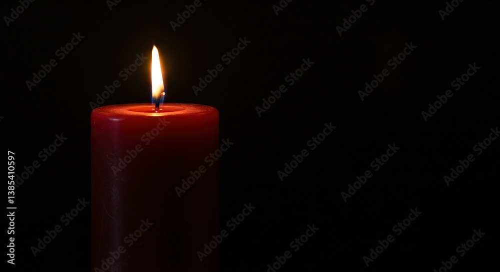 Red pillar candle burning in darkness Red pillar candle burning in darkness