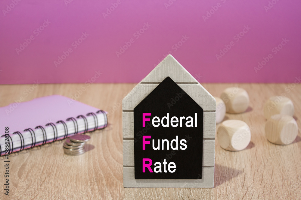 FEDERAL FUNDS RATE symbol. Black board with words FEDERAL FUNDS RATE. Beautiful purple background. Notebook and silver coins on the table. Business concept.