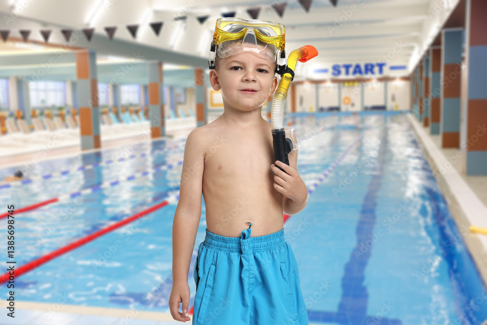 Cute little boy in trunks with snorkeling equipment at indoor swimming pool