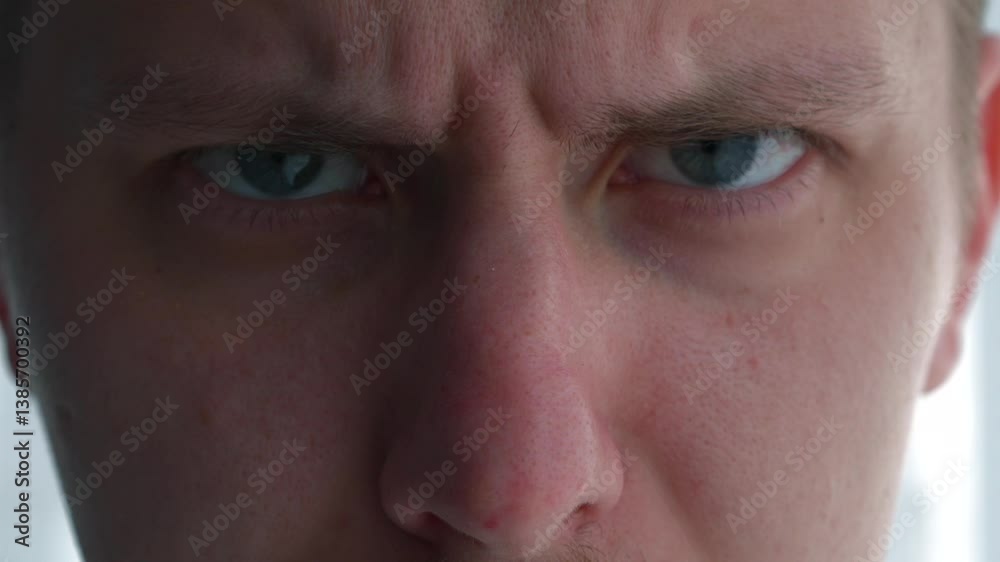 Wrinkles on a person's forehead.
Angry look on a guy.
A person looks at the camera and wrinkles his forehead