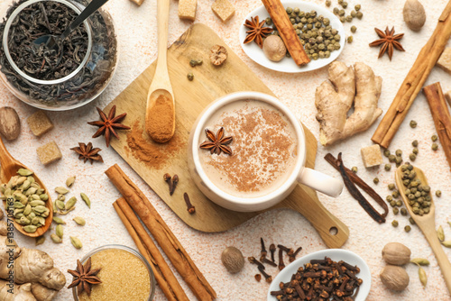 Fototapeta Naklejka Na Ścianę i Meble -  Aromatic Masala tea in cup, spices, dry leaves and brown on color textured table, flat lay