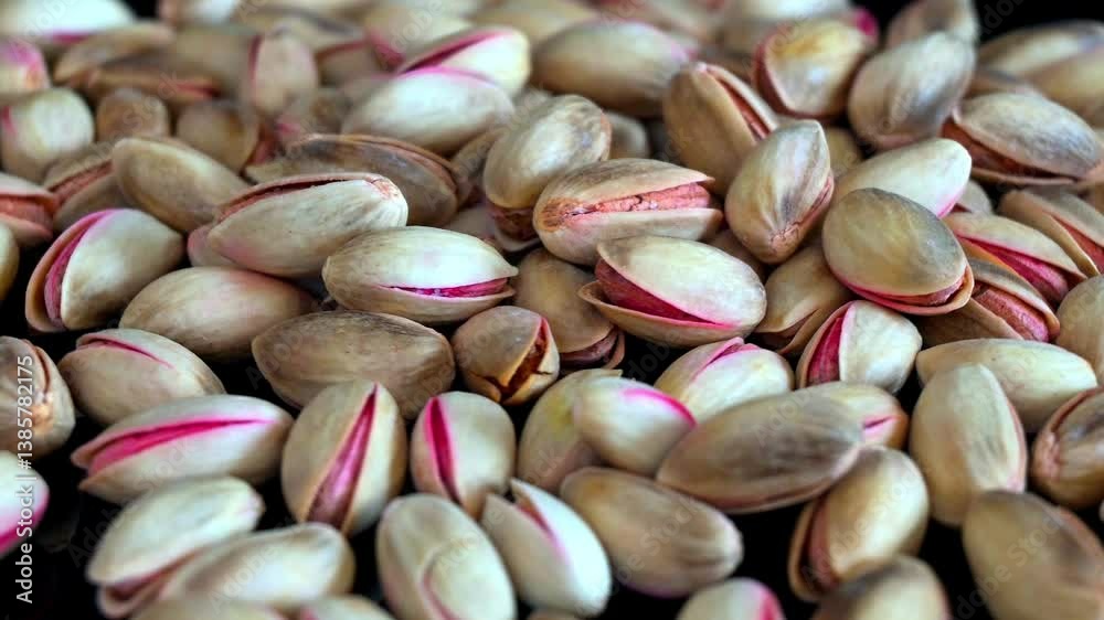Close up static shot footage shows a lot of unpeeled pistachio nuts rotating. Food concept.