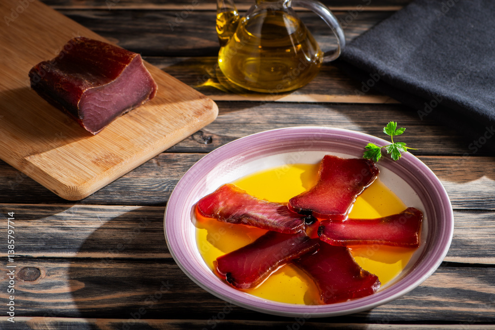 Slices of salt-cured tuna loin on a plate with olive oil, mojama, a typical dish from the coasts of Andalusia and Murcia, an ancestral recipe.