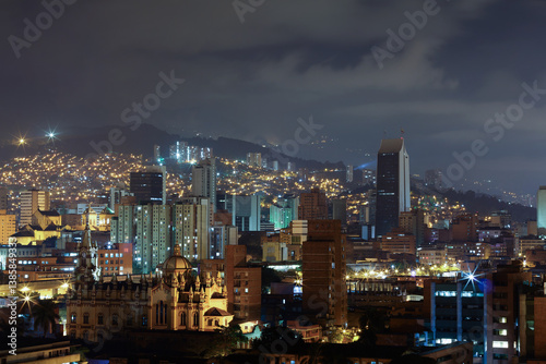 Obraz na płótnie Breathtaking night view of Medellín, Medellin, Antioquia, Colombia, with illuminated skyscrapers and historic architecture. The city glows against the Andean mountains, creating a urban landscape. w salonie