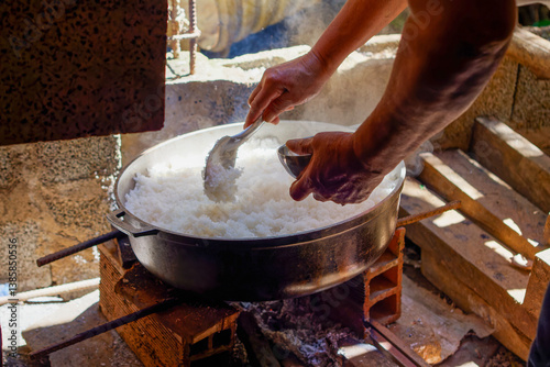 Cooking rice over open flames in a rustic kitchen in Medellín, Medellin, Antioquia, Colombia. A glimpse into daily life and traditional culinary practices in a humble neighborhood home