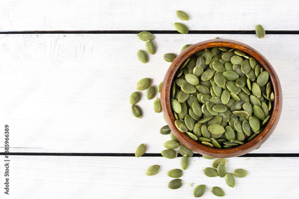 Delicious pumpkin seeds on wooden background