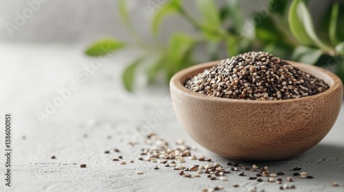 A small wooden bowl filled with sesame seeds, placed on a white surface with some scattered seeds around
