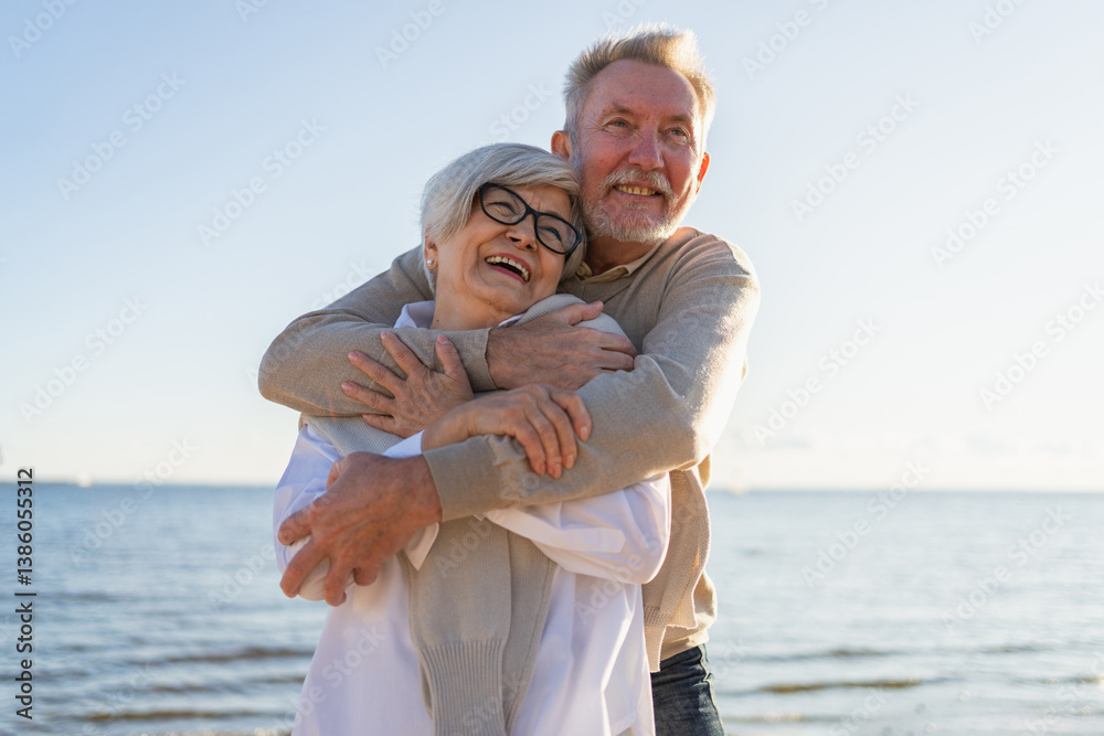 Obraz premium Senior mature couple hugging enjoying outdoor recreation walking on beach. Old husband wife embracing with tenderness love enjoying sweet bonding. Grandmother grandfather together. Family moment love