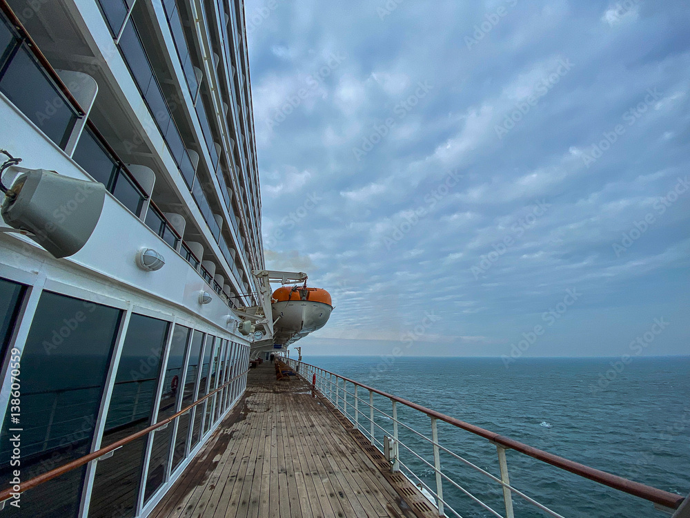 Views onto outdoor teak balcony terrace veranda promenade boat deck of ocean liner cruiseship cruise ship with chairs and loungers at sea during Transatlantic Crossing to New York on beautiful sun day