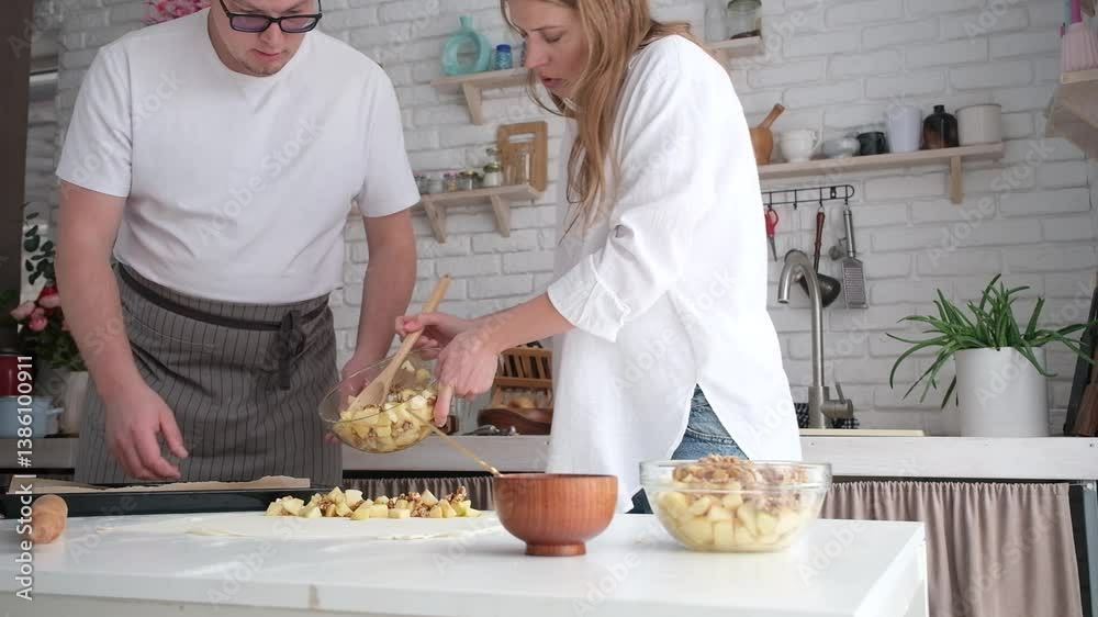 happy couple having wonderful time while cooking apple strudel in a cheerful atmosphere together. Kitchen, housework, home, relationship