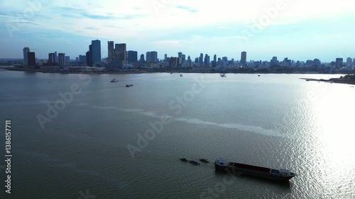 Cargo ship sailing near Phnom Penh skyline. Amazing aerial view flight drone