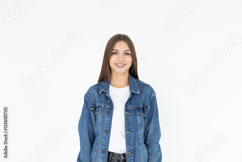 A woman with black hair in a denim jacket and white shirt smiles