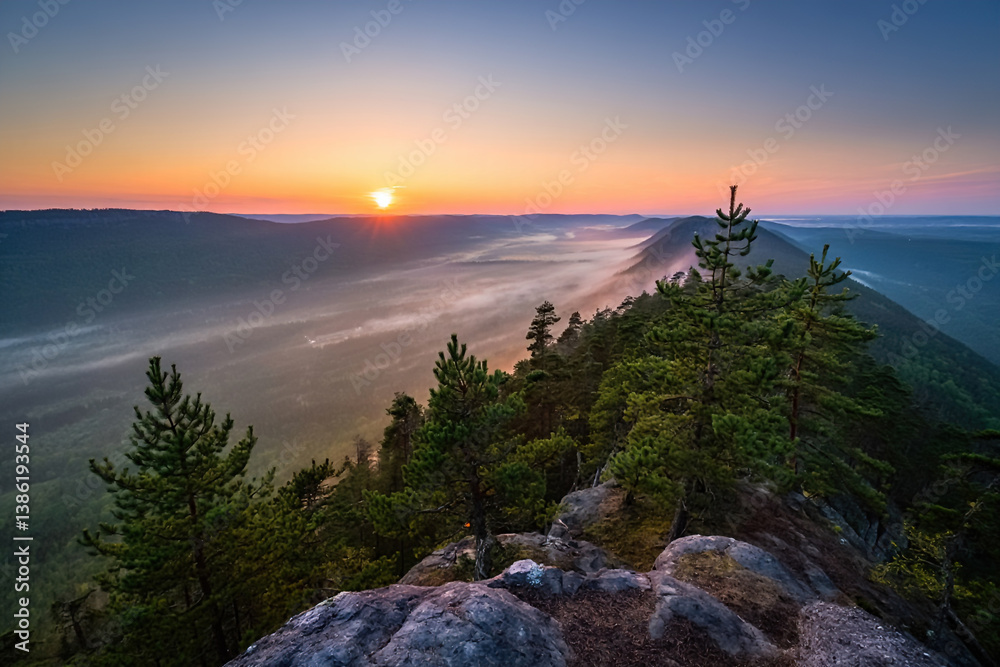 Sunrise on top of mountains, pine trees, foggy valley below, colorful sky, beautiful landscape with mountains