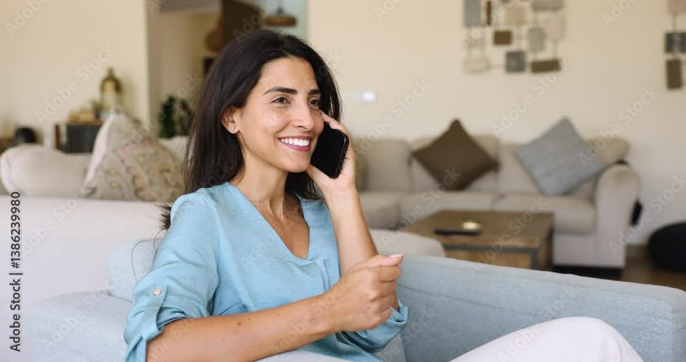 Happy positive young Latin woman enjoying phone call, communication, speaking on mobile phone, chatting to friend on cellphone, relaxing in comfortable armchair, talking on cell, smiling, laughing Happy positive young Latin woman enjoying phone call, communication, speaking on mobile phone, chatting to friend on cellphone, relaxing in comfortable armchair, talking on cell, smiling, laughing