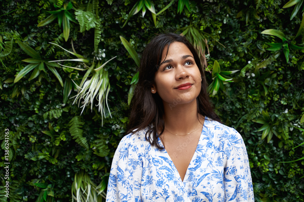 Beautiful young mixed race woman portrait looking up on green tropical foliage background