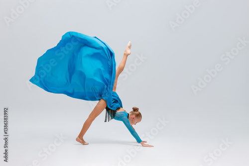 A ballerina performs an acrobatic move, balancing on one hand with a leg elevated. She wears a leopard print costume and a flowing blue skirt, skilled cheerleader