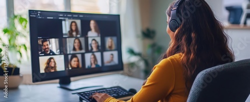 Woman in headphones attending a virtual meeting on a computer at home office.