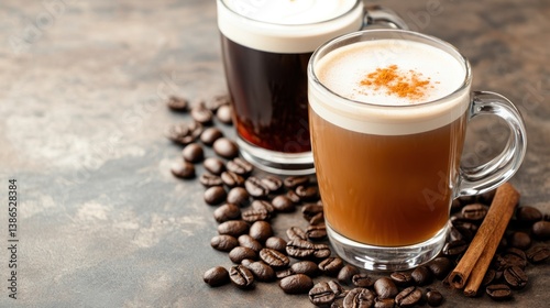 Close-up of two coffee drinks with creamy froth, rich coffee beans, and cinnamon on a textured surface
