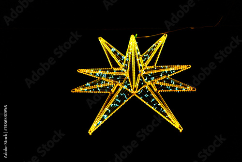 Obraz na płótnie Illuminating the night, a magnificent starburst of golden and teal LED lights. Geometric star, crafted from glowing LED lights, creating a striking silhouette against the dark backdrop
w salonie