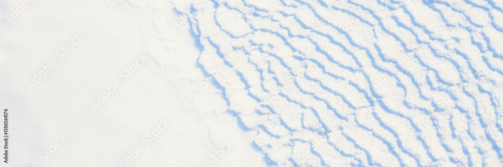 Beautiful winter background with snowy ground. Natural snow texture. Wind sculpted patterns on snow surface. Wide panoramic texture for background and design.