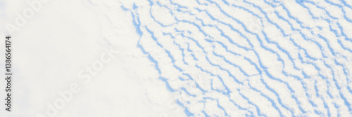 Obraz na płótnie Beautiful winter background with snowy ground. Natural snow texture. Wind sculpted patterns on snow surface. Wide panoramic texture for background and design. w salonie
