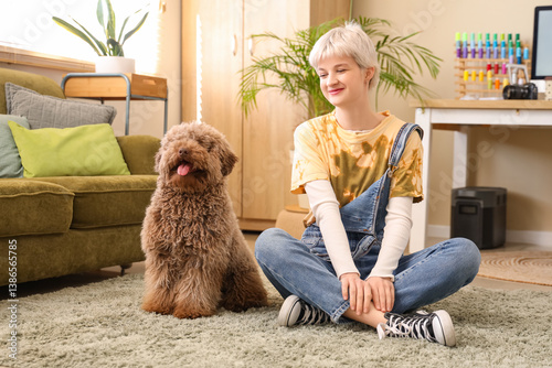 Young woman sitting on floor with Poodle dog near workplace in light office