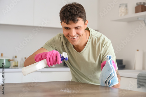 Young man cleaning table in...