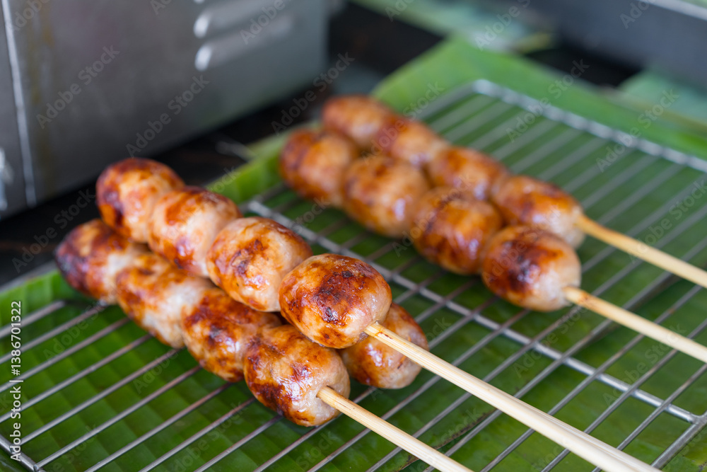 northeastern sausage on stick or skewered and arranged grilled burn on grille and banana leaf or isan sausage and barbecue meatball for traditional thai street food in local thailand or esan sausages northeastern sausage on stick or skewered and arranged grilled burn on grille and banana leaf or isan sausage and barbecue meatball for traditional thai street food in local thailand or esan sausages