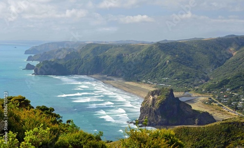 looking down on iconic lion rock, coastal headlands,  and black sand of  piha beach from on a summer day  from the mercer bay loop trail on the west coast of north island of new zealand, near auckland