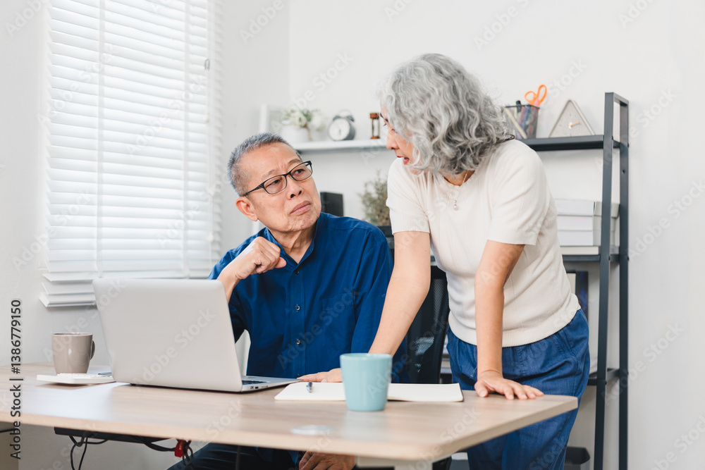 Obraz premium Elderly couple discussing something while working on laptop in home office setting.