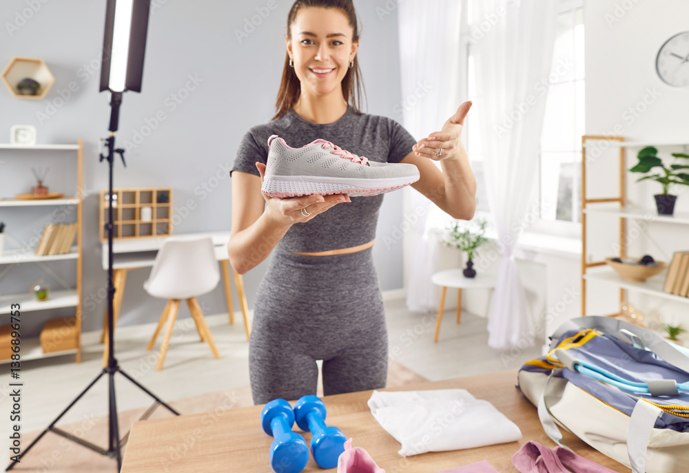 Fit sporty young woman fitness model blogger making commercial social media marketing collaboration integration with sports footwear brand, filming promotion video, holding and showing shoe at camera