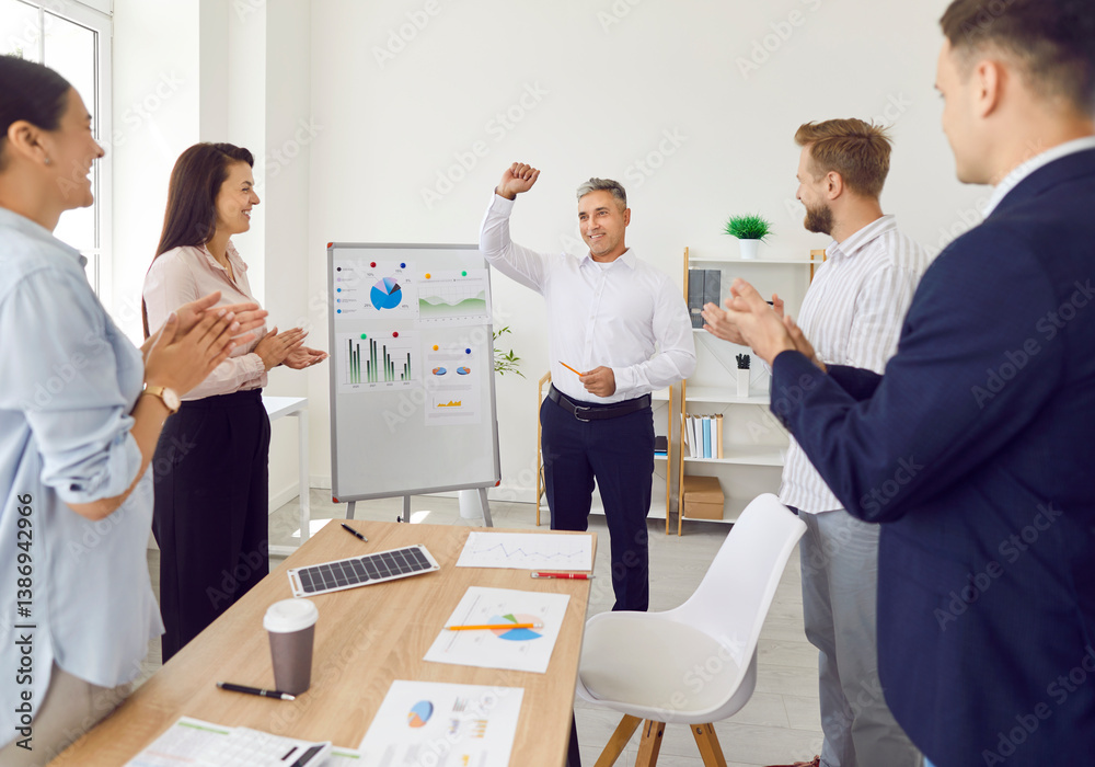 Obraz premium Happy team celebrating success and leadership. Group of young people applauding and thanking coworker for business expertise and analytics presentation at whiteboard with infographic charts and graphs