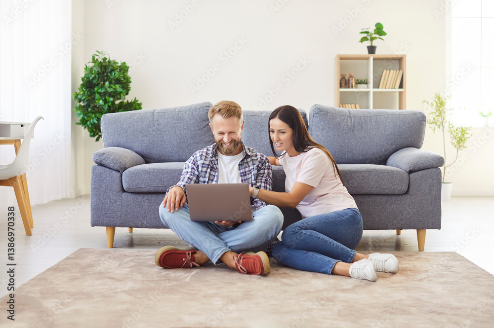 Young happy family couple using laptop, getting good news sitting restring on carpet near cozy sofa, chatting online, buying goods, ordering services on internet, e -shopping websurfing, relax weekend Young happy family couple using laptop, getting good news sitting restring on carpet near cozy sofa, chatting online, buying goods, ordering services on internet, e -shopping websurfing, relax weekend