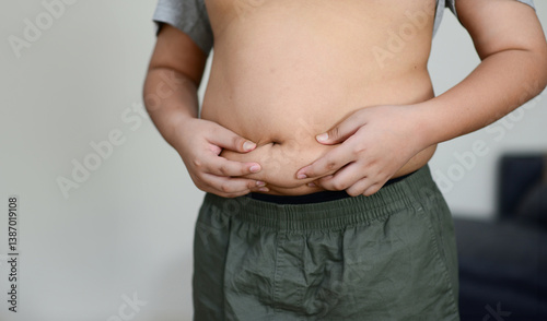 Obraz na płótnie A fat child with a fat belly holds his stomach with his hands. w salonie