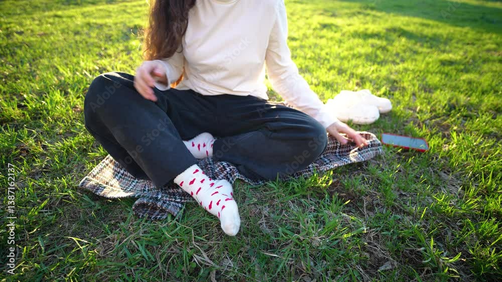 A girl without a face sits on the grass, puts her smartphone aside and sits in a meditation pose, the concept of relaxation without gadgets A girl without a face sits on the grass, puts her smartphone aside and sits in a meditation pose, the concept of relaxation without gadgets