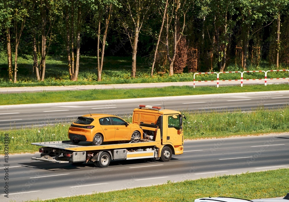 Tow truck with car driving on empty road